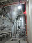 Used Niro Spray Tower Dryer. Originally designed for 12,500 pounds / hour of water evaporation. The dryer capacity was increased to 15,000 pounds / hour at 65,000 SCFM of air flow.  The Dryer is constructed of 316 L Stainless Steel. The dryer is a Standard Tall Form Dryer equipped with an integral static Fluid Bed Dryer and external Vibratory Fluid Bed Cooler. Both beds have heaters and the VFB also had a Cooler. The Dryer was equipped with fines return and agglomeration capabilities as an opti