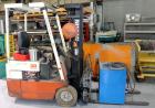 Used Nissan 3 Wheel Sit Down Electric Forklift, Model OT30, Type E. 2700 Pound capacity, triple mast. Includes a charger.