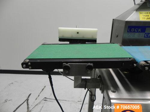 Used Lock Model Weigh Chek CK2500 Belt Checkweigher. Machine is capable of speeds up to 300 cases per minute (dependent on case size). Has a package weight range of 10 of 2500 g and a weight cell cap...