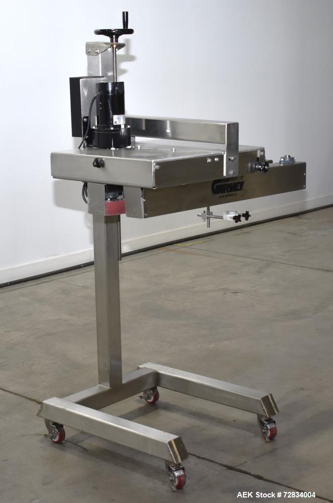 Used Garvey Side Belt Gap Transfer Conveyor. (2) Belts, approximate 39" long x 2" wide. Adjustable height. Mounted on casters. Last used with Video Jet coder for bottom date coding. 1/60/115 Volt.
