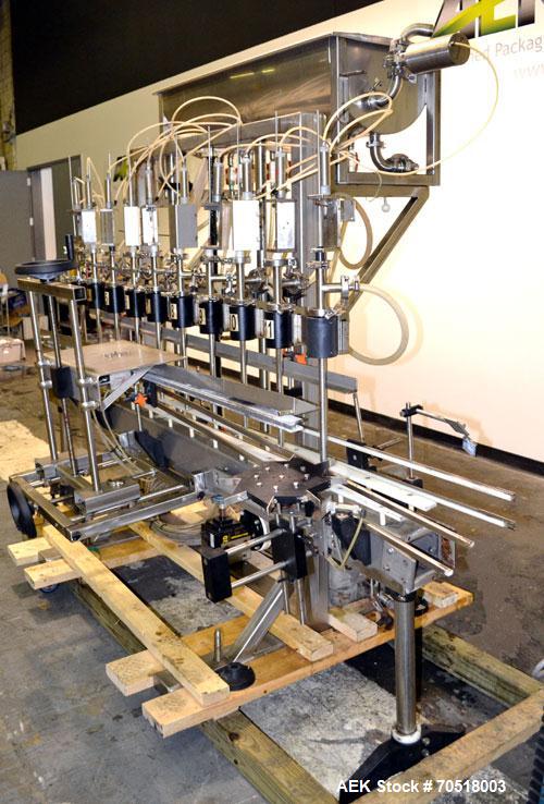 Used Fluid Packaging Solutions 12 Head Inline Automatic Time / Gravity Liquid Filler. Fabricated with 4-1/2" wide x 180" long table top chain conveyor, 5/8" nozzles with positive shut-off valves, div...