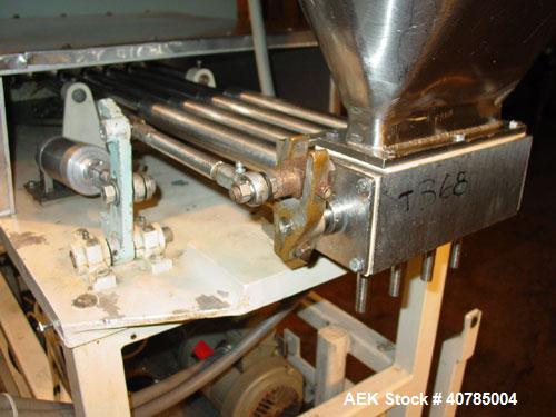 Used Simplex 4 Head Filler. Stainless steel nozzles 2" long x 3/16" opening, approximate 12 oz capacity per stroke, 28" diameter x 24" deep stainless steel hopper with cover. Mounted on a carbon stee...