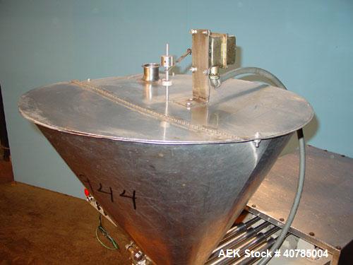 Used Simplex 4 Head Filler. Stainless steel nozzles 2" long x 3/16" opening, approximate 12 oz capacity per stroke, 28" diameter x 24" deep stainless steel hopper with cover. Mounted on a carbon stee...