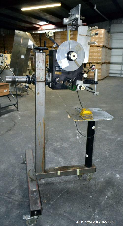 Used LSI Loose Loop Print & Apply Labeler, Model 1360, capable of 120 products per minute. Can accommodate up to 4" x 4" labels. Foot pedal controls. Mounted on a stand with casters. Missing printer....