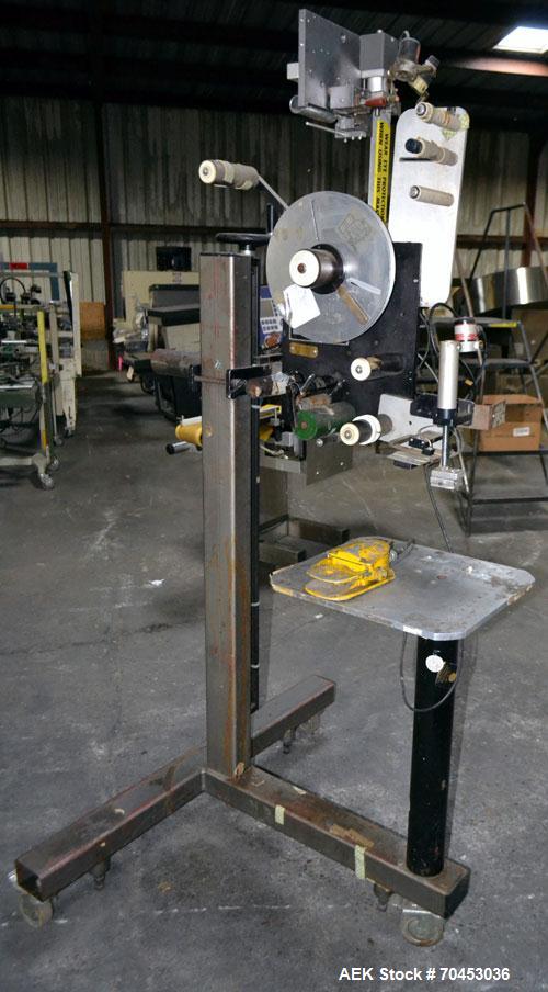 Used LSI Loose Loop Print & Apply Labeler, Model 1360, capable of 120 products per minute. Can accommodate up to 4" x 4" labels. Foot pedal controls. Mounted on a stand with casters. Missing printer....