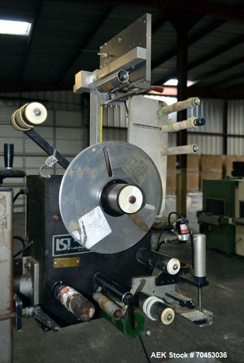 Used LSI Loose Loop Print & Apply Labeler, Model 1360, capable of 120 products per minute. Can accommodate up to 4" x 4" labels. Foot pedal controls. Mounted on a stand with casters. Missing printer....