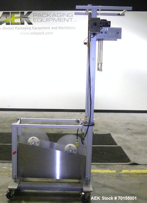 Used Axon Corporation EZ-100 Tamper Evident Band and Sleeve Label Applicator capable of speeds up to 150 packages per minute. Stainless steel design. Has vertical perforation, power unwind station an...