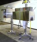 Used Axon Corporation EZ-100 Tamper Evident Band and Sleeve Label Applicator capable of speeds up to 150 packages per minute. Stainless steel design. Has vertical perforation, power unwind station an...