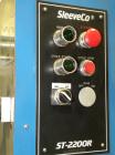 Used SleeveCo Model ST-2200R Stretch Sleeve Applicator capable of speeds up to 60 bottles per minute. Currently set up on round gallon containers, has film registration. Machine footprint 48