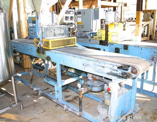 USED: Guillotine cutter. (1) 13" wide blade. Air operated single ram. Mounted on a table with a 12" wide x 10' long rubber belt conveyor. Driven by an approximately 2 hp gearmotor. Mounted on casters.