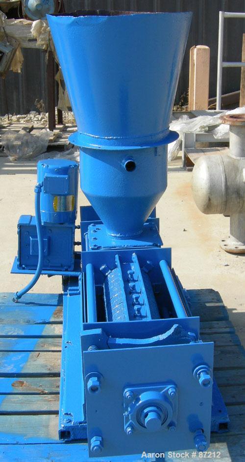 USED: Screw press, carbon steel. Approximate 6" diameter x 21" long chamber. 4" top feed with hopper. Screw driven by a 3/4 HP, 3/60/209-230/460 volt, 1725 RPM gear motor. Base mounted.