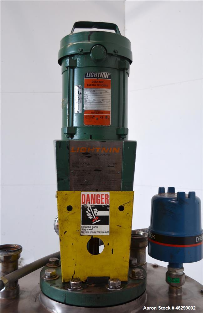 Used Tank, Approximately 40 Gallons, 304 Stainless Steel, Vertical. 20" Diameter x 30" straight side. Bolt-on flat top with 1/4 hinged cover, dished bottom. Top entering Lightnin agitator model XJC-3...