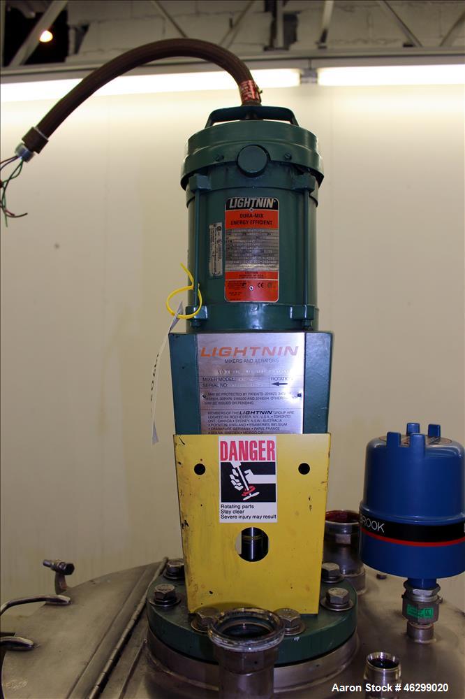 Used Tank, Approximately 40 Gallons, 304 Stainless Steel, Vertical. 20" Diameter x 30" straight side. Bolt-on flat top with 1/4 hinged cover, dished bottom. Top entering Lightnin agitator model XJC-3...