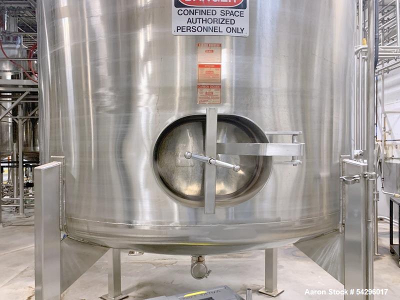 Used Stainless Steel Tank, Approximate 1,000 gallon. Center bottom outlet, side bottom manway, on (4) stainless steel legs.