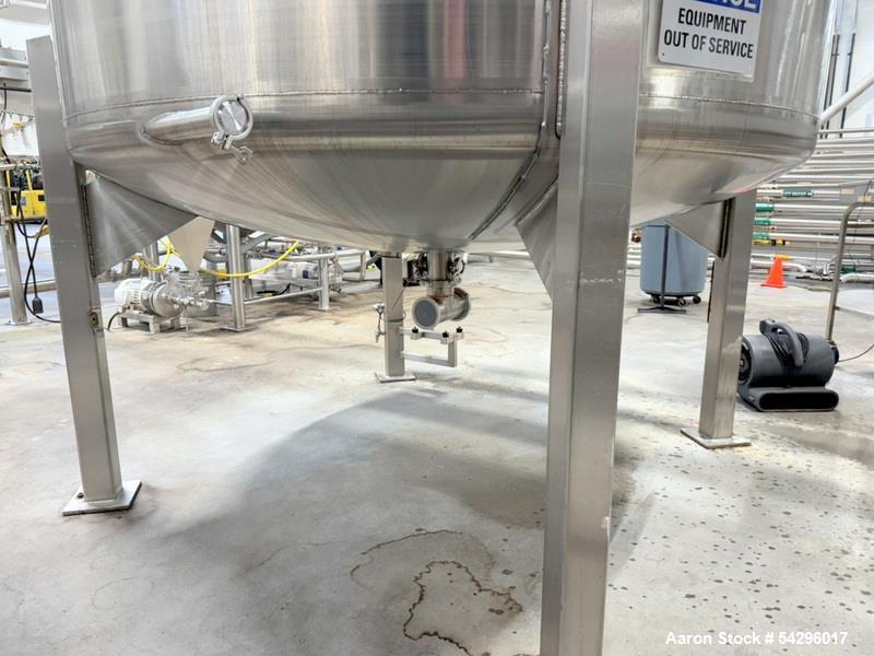 Used Stainless Steel Tank, Approximate 1,000 gallon. Center bottom outlet, side bottom manway, on (4) stainless steel legs.