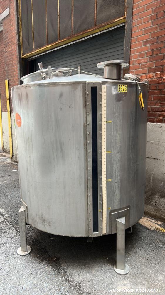 Used Tank, Approximate 650 Gallon, Stainless Steel, Vertical. Approximate 60" diameter x 54" straight side, coned top, sloped bottom. Mounted on 4 stainless legs.
